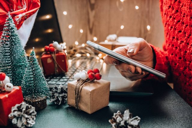 Una chica consulta su teléfono móvil, con decoración de Navidad al fondo.
